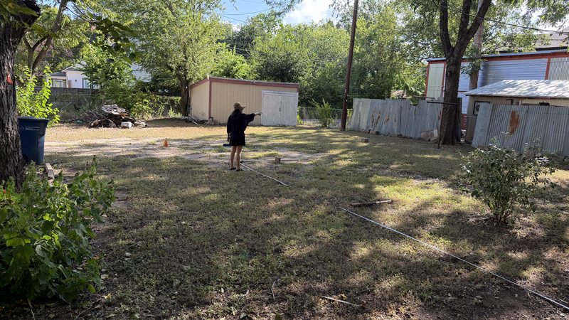 Ella marking building corners with stakes and tape at 81 Chalmers