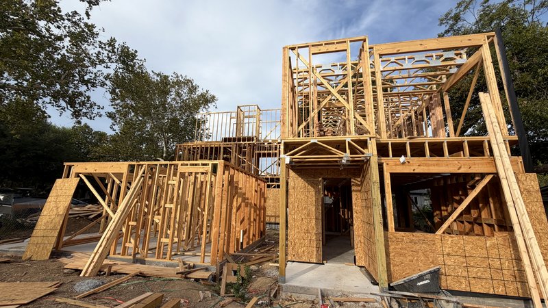 All three frames with garage openings framed and second-floor decks on