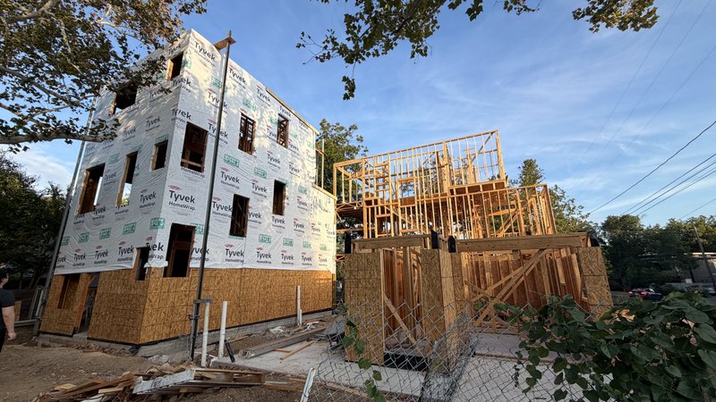 Home 1 wrapped in Tyvek house wrap, Homes 2 and 3 framing behind