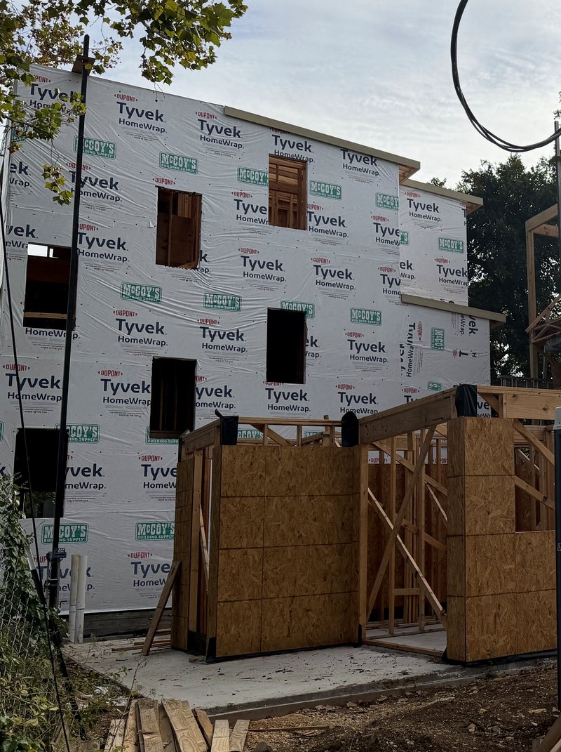 Home 1 fully wrapped in weather barrier with garage framing in front