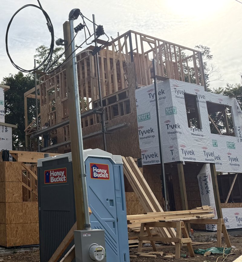 Home 2 wrapped with third floor framing above, power pole and meter in front